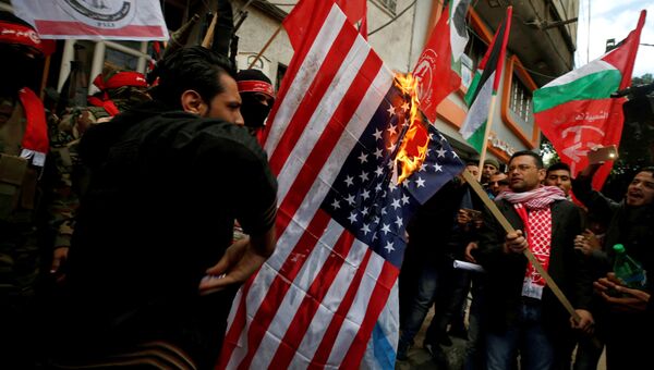 Палестинцы сжигают флаг США во время протеста против решения Трампа признать Иерусалим столицей Израиля в городе Газа. 7 декабря 2017