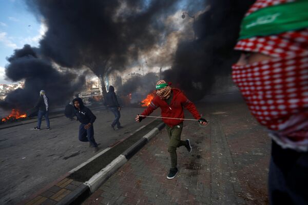 Палестинские протестующие во время столкновений с израильскими военными в районе города Рамалла на Западном берегу
