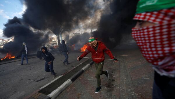 Палестинские протестующие во время столкновений с израильскими военными в районе города Рамалла на Западном берегу. 7 декабря 2017