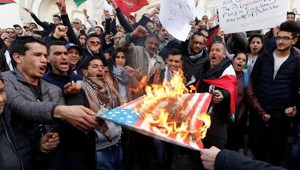 Протестующие сжигают флаг США во время протеста против решения Дональда Трампа признать Иерусалим столицей Израиля в Тунисе. 7 декабря 2017