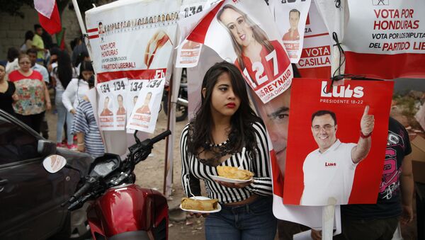 Женщина рядом с агитационным плакатом в поддрежку кандидата в президенты от Либеральной партии Луиса Селайя. Архивное фото