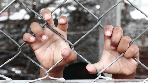 Руки ребенка, сжимающие забор