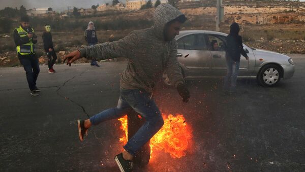 Протестующие во время столкновений на границе Палестины и Израиля в районе Рамаллы. 10 декабря 2017