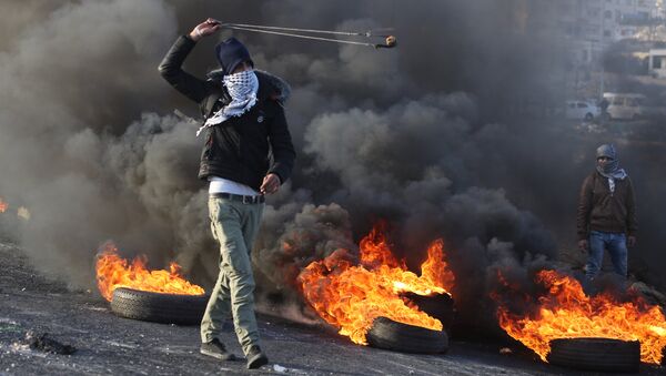 Протестующие во время столкновений на границе Палестины и Израиля в районе Рамаллы. 11 декабря 2017
