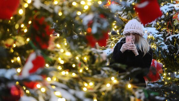 Девушка фотографируется у ели, оформленной для фестиваля Путешествие в Рождество. Архивное фото
