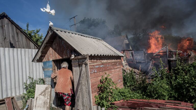 Последствия артобстрела Славянска украинскими военными. Хозяйка горящего дома входит в голубятню