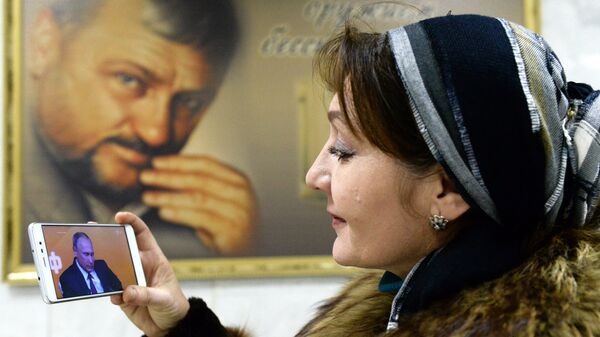 Жительница Грозного смотрит трансляцию пресс-конференции президента РФ Владимира Путина