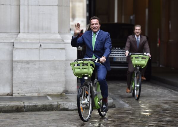 Бывший губернатор американского штата Калифорния Арнольд Шварценеггер едет на велосипеде в Париже. 11 декабря 2017 года