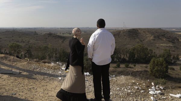 Израильтяне на фоне панорамы Сектора Газа на окраине израильского города Сдерот. Архивное фото
