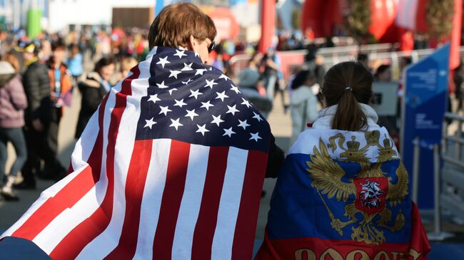 Молодые люди в национальных флагах США и России 