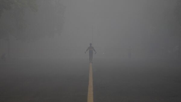 Человек на дороге, накрытой туманом, в Нью-Дели, Индия. 21 декабря 2017