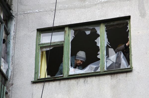Женщина у окна жилого дома в центре города Ясиноватая, пострадавшего в результате обстрела. 21 декабря 2017