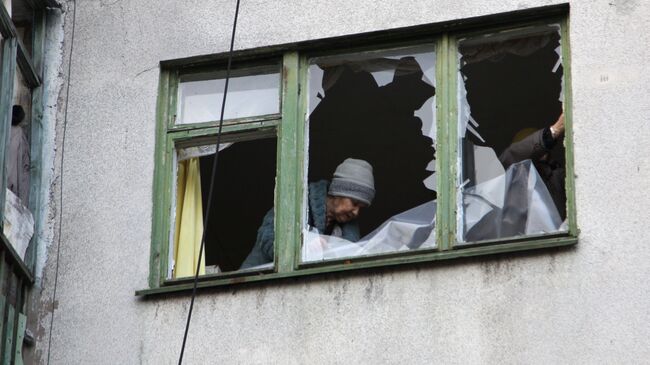 Женщина у окна жилого дома в центре города Ясиноватая, пострадавшего в результате обстрела. 21 декабря 2017