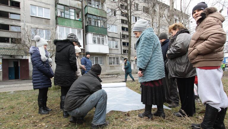 Жителям домов города Ясиноватая, пострадавшим в результате обстрела, выдают пленку, чтобы закрыть разбитые окна. 21 декабря 2017