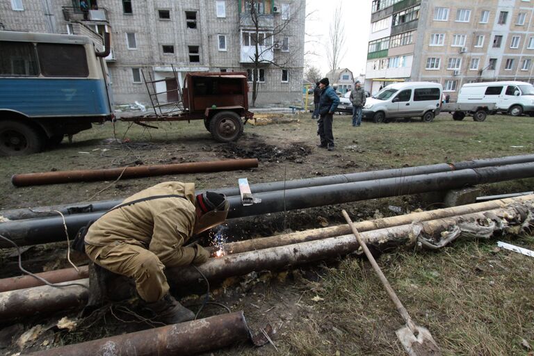 Сотрудник ЖКХ ремонтирует трубы жилого дома в городе Ясиноватая, пострадавшего в результате обстрела. 21 декабря 2017