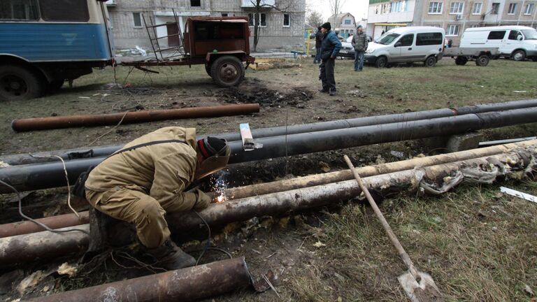 Сотрудник ЖКХ ремонтирует трубы жилого дома в городе Ясиноватая, пострадавшего в результате обстрела. 21 декабря 2017