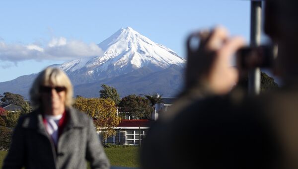 Женщина фотографируется на фоне горы Таранаки в Новой Зеландии