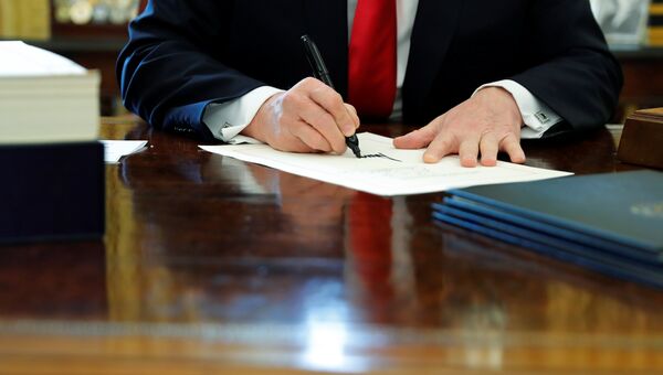 Дональд Трамп подписывает документ в Овальном кабинете Белого дома
