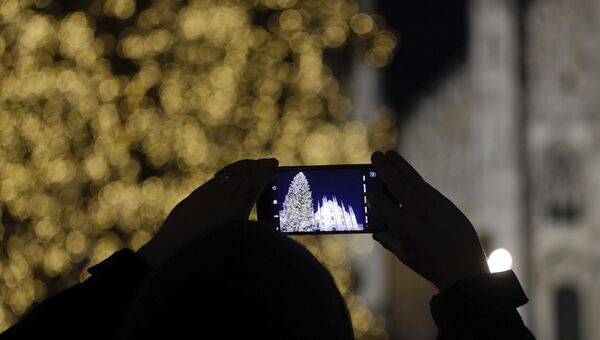 Мужчина фотографирует рождественскую елку в Милане, Италия. Архивное фото