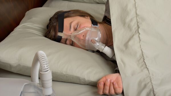 Женщина спит с аппаратом, препятствующим остановке дыхания
