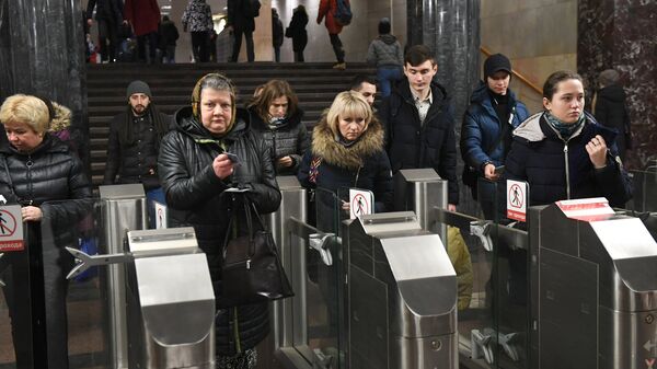 Пассажиры проходят через турникеты в московском метрополитене