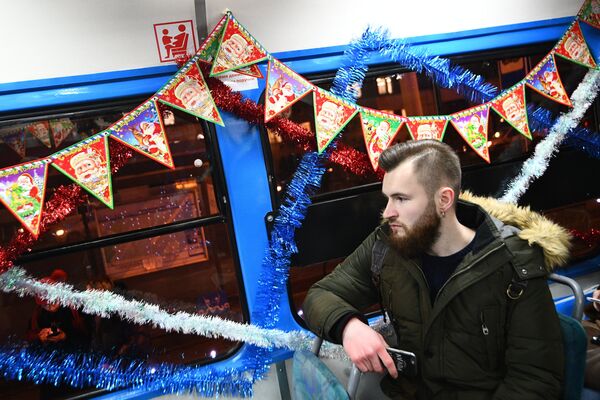 Пассажир в салоне новогоднего трамвая, украшенный яркими светодиодными огнями, в Москве