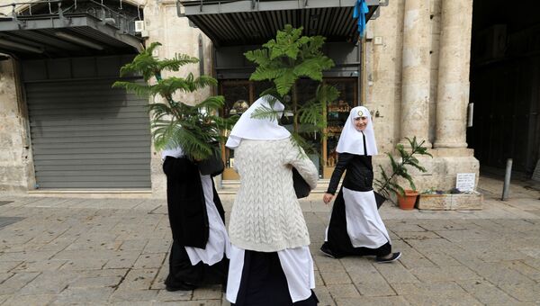 Монахини несут рождественские елки, ежегодно раздаваемые муниципалитетом Иерусалима в Старом городе. 21 декабря 2017 года