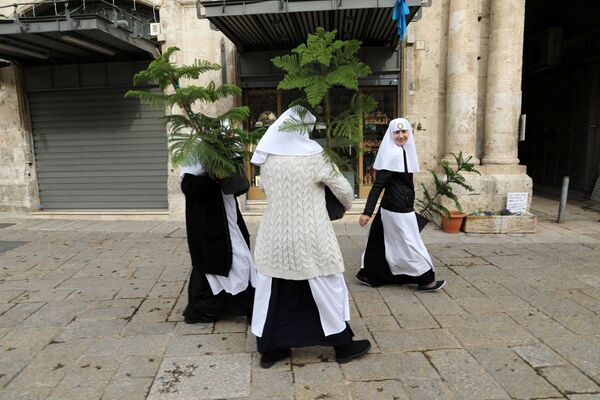 Монахини несут рождественские елки, ежегодно раздаваемые муниципалитетом Иерусалима в Старом городе. 21 декабря 2017 года