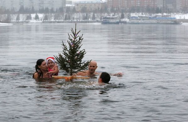 Члены зимнего плавательного клуба Криофил с новогодней елкой в реке Енисее в Красноярске. 23 декабря 2017 года
