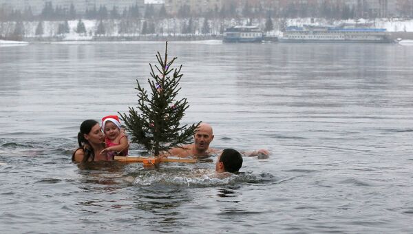 Члены зимнего плавательного клуба Криофил с новогодней елкой в реке Енисее в Красноярске. 23 декабря 2017 года