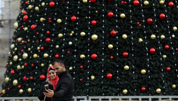 Люди делают селфи перед рождественской елкой в ​​городе Вифлеем на Западном берегу. 19 декабря 2017 года