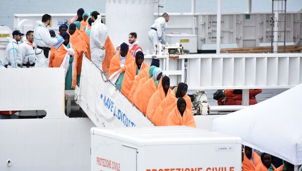 Мигранты высаживаются с судна береговой охраны Италии после спасательной операции в море. 8 января 2018
