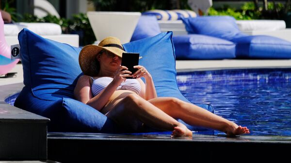 Девушка отдыхает у бассейна на территории отеля в Таиланде