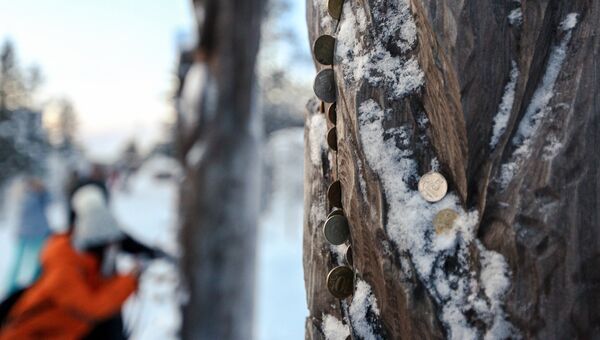 Китайские туристы оставляют монетки у деревянных идолов в саамской деревне Самь-Сыйт в поселке Ловозеро Мурманской области
