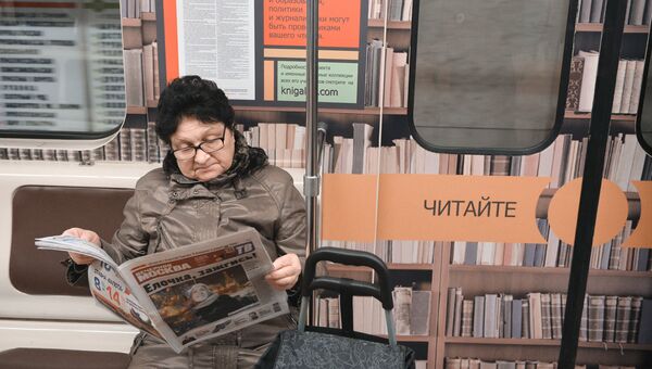Женщина читет газету в метро. Архивное фото