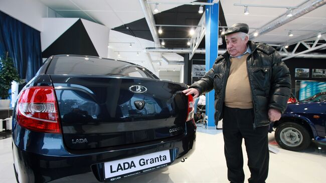 Мужчина выбирает автомобиль Лада Гранта в автосалоне