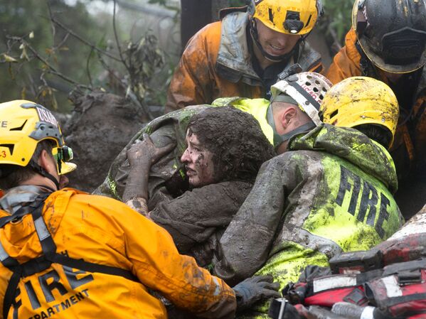 Сотрудники спасательных служб несут женщину, спасенную из дома, рухнувшего после оползня в Монтесито, штат Калифорния, США. 9 января 2018