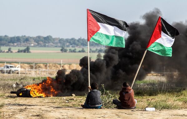 Палестинские демонстранты размахивают своим национальным флагом возле границы между Израилем и Газой. 9 января 2018 год