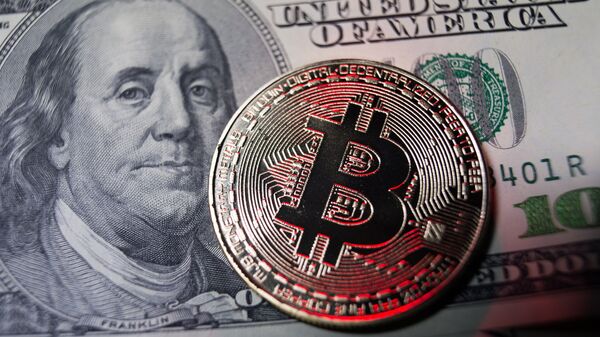 Монета логотипом криптовалюты биткоин и 100-долларовая купюра. Архивное фото