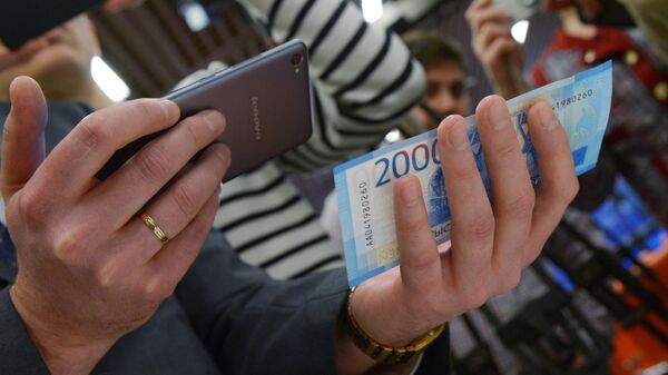 Мужчина сканирует купюру телефоном, на котором установлено мобильное приложение. Архивное фото