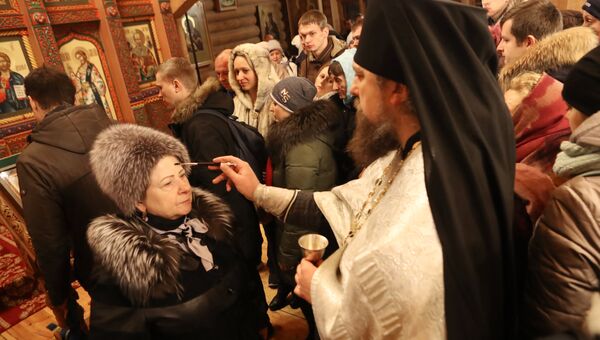 Верующие со священнослужителем во время традиционного праздничного молебна в Крещенский сочельник в Храме Святителя Николая в Измайловском Кремле в Москве