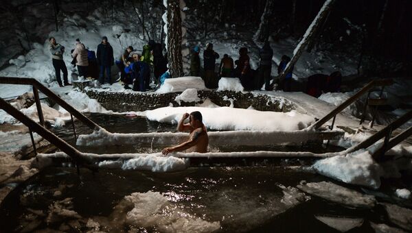 Верующие купаются в купели во время традиционного праздничного купания в Крещенский сочельник на источнике Святой ключ в Искитимском районе Новосибирской области