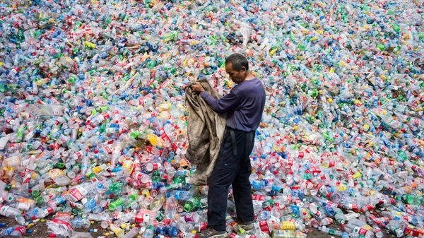 Китайский рабочий, сортирующий пластиковые бутылки для переработки. Архивное фото