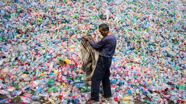 Китайский рабочий, сортирующий пластиковые бутылки для переработки, на окраине Пекина. Архивное фото