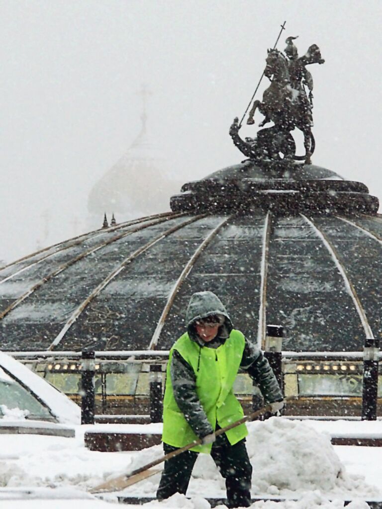 Работник городской коммунальной службы убирает снег на Манежной площади в Москве