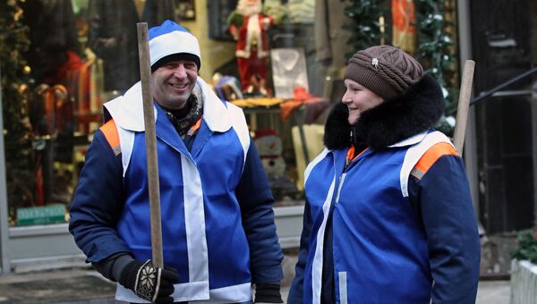 Сотрудники коммунальной службы в новогодних жилетах и шапочках во время проведения акции Утепляем Москву