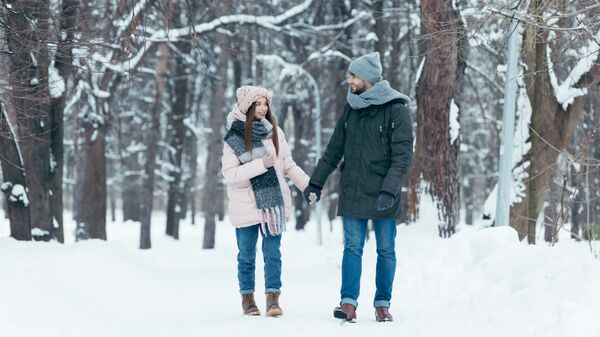 Молодая пара во время прогулки в парке зимой. Архивное фото
