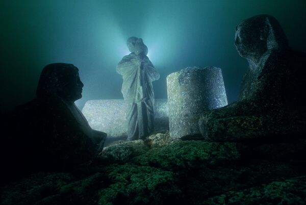Статуя жреца с изображением бога Осириса на руках и два сфинкса  - выставка Затонувшие сокровища Египта  