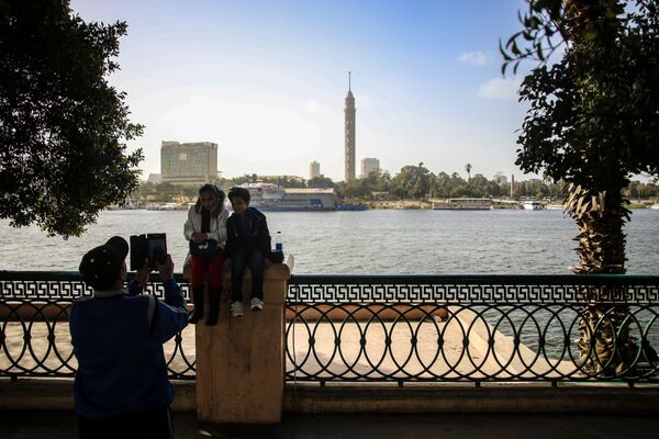 Дети фотографируются на набережной в Каире. На дальнем плане: Каирская телебашня