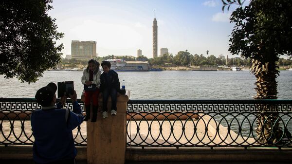 Дети фотографируются на набережной в Каире. На дальнем плане: Каирская телебашня